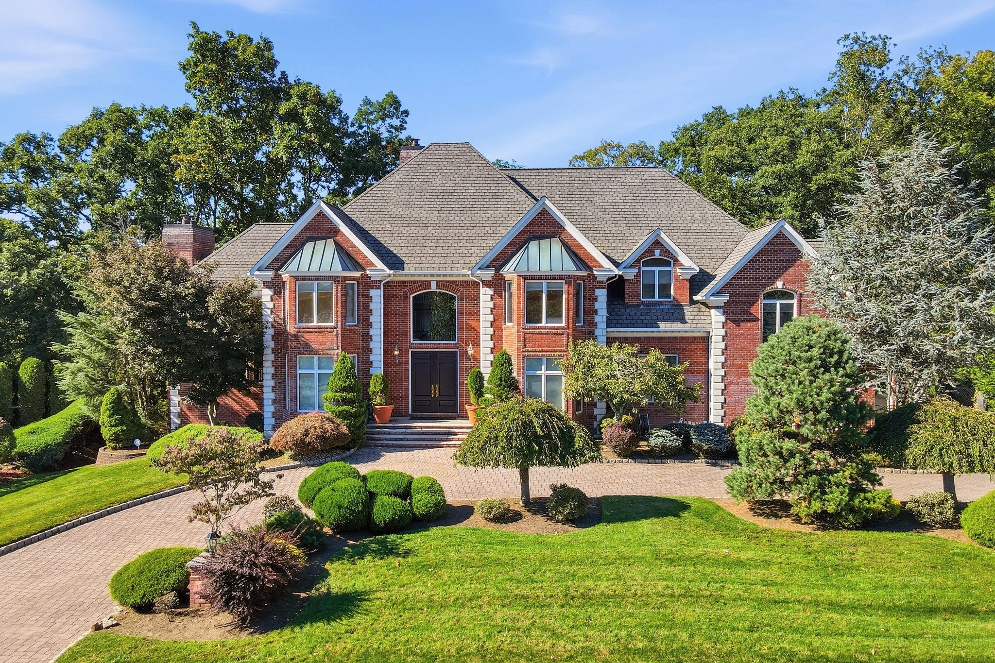 All brick Colonial front elevation with circular paver driveway and landscaped lawn at 54 Burnet Hill Road, Livingston